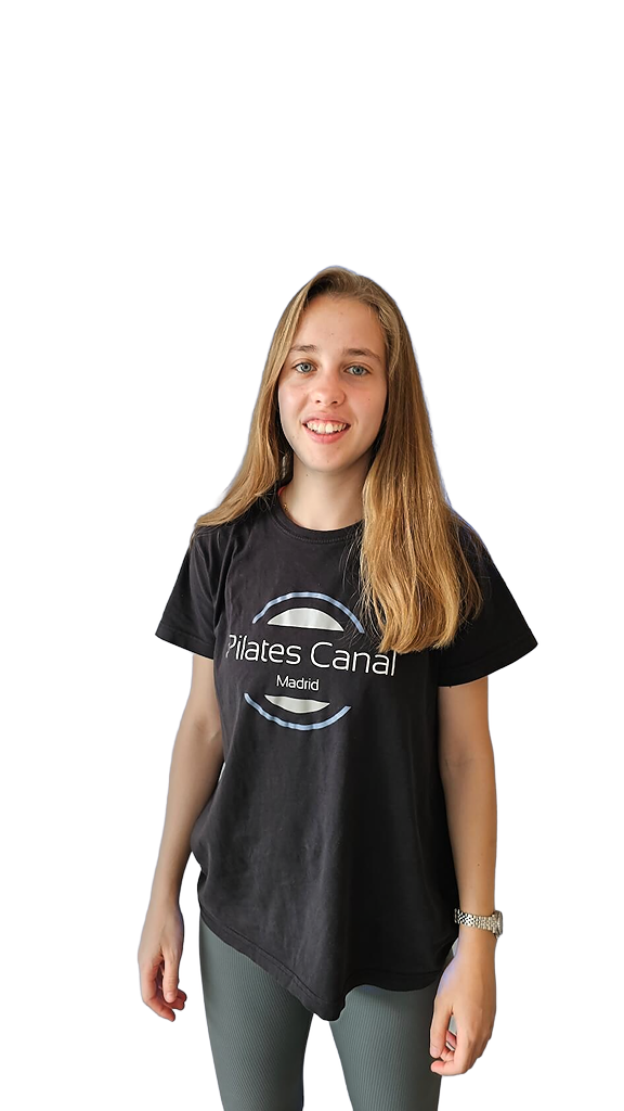 Pilates Canal Madrid Una persona de pelo largo y rubio está de pie sonriendo, encarnando el vibrante espíritu de un "Centro de bienestar en Madrid". Lleva una camiseta negra de "Pilates Canal Madrid" y pantalones oscuros. El fondo es transparente.